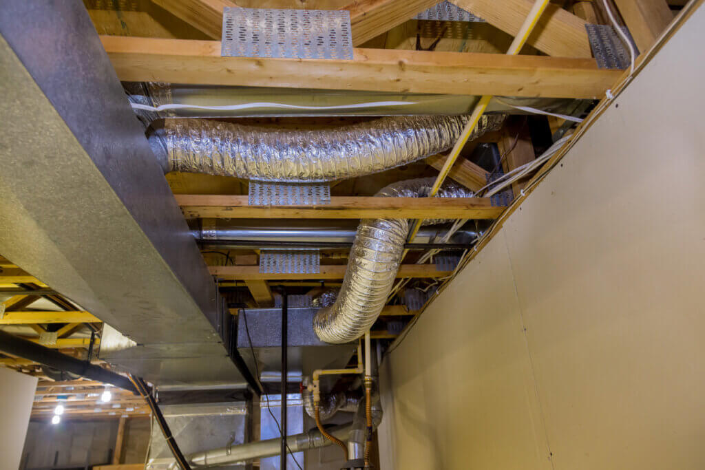 Framed building installation of air conditioner and heating ductwork in ceiling